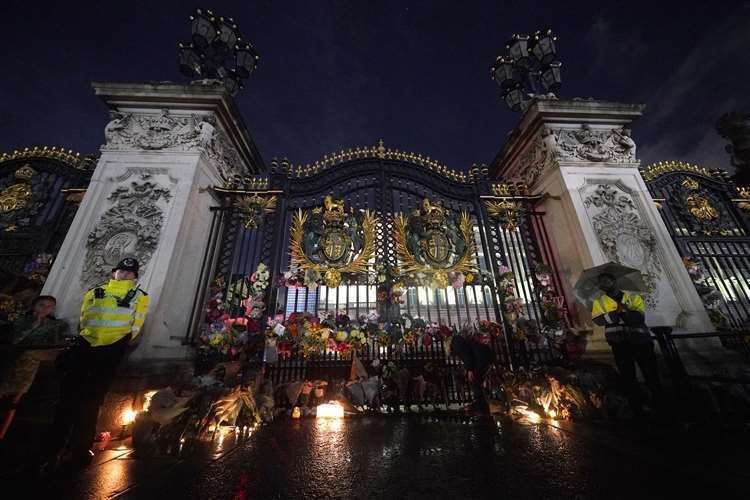 A mourner lays floral tributes left outside Buckingham Palace in central London, following the announcement of the death of the Queen (Yui Mok/PA) (61597423)