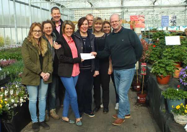 Bex Lee receives a cheque from staff at Delamore Plants