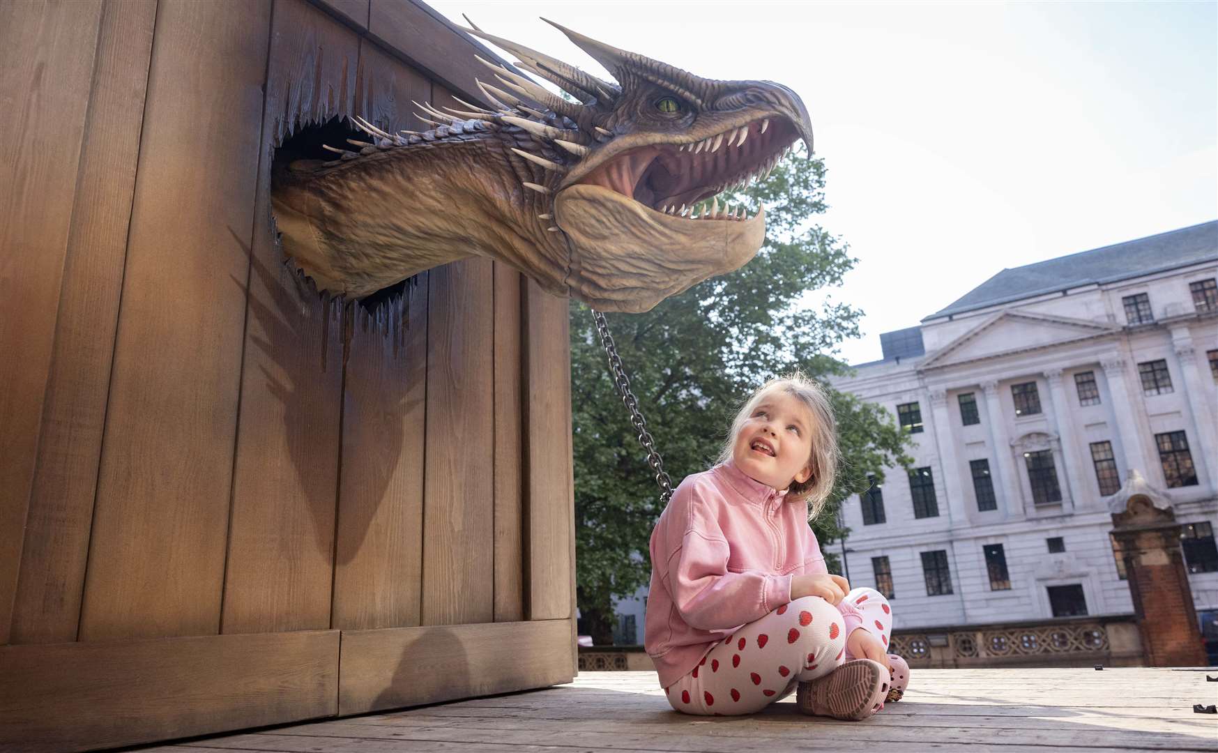 Rae McFarlane, aged five, sits by the 25-ft-long animatronic Hungarian Horntail (Matt Alexander/PA)
