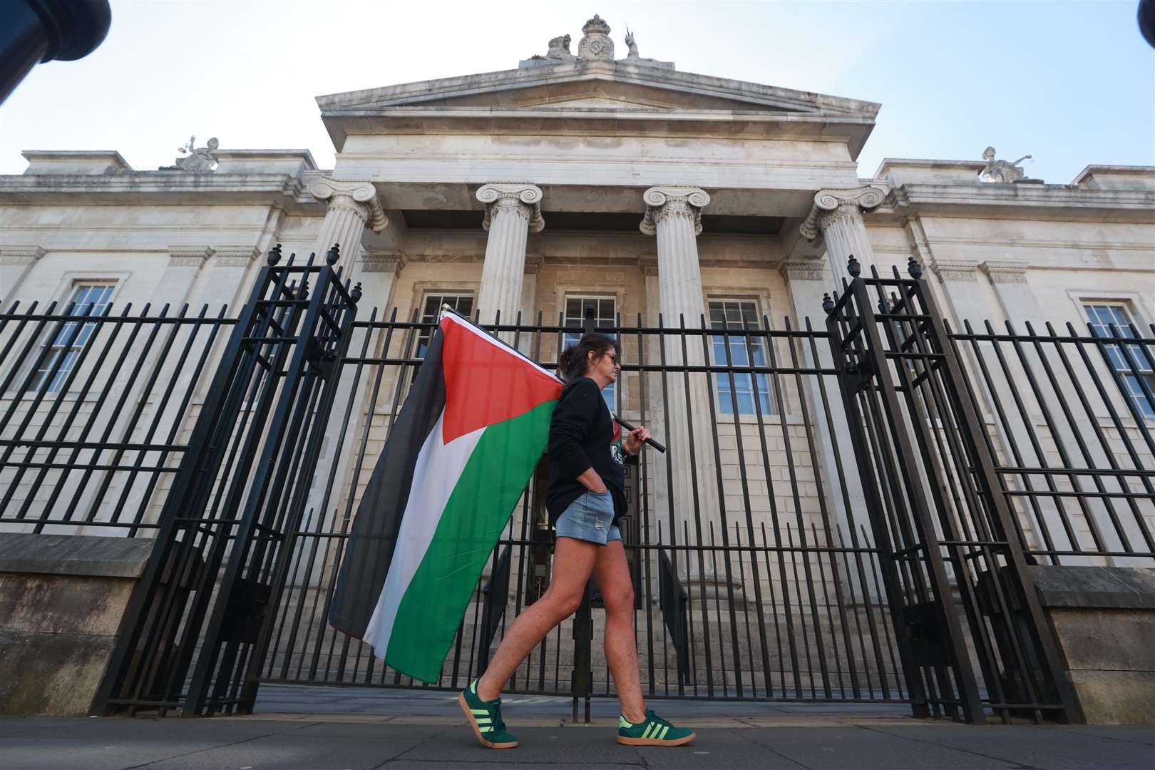 Dr Sandra McDermott carries a Palestinian flag as she walks past Derry Magistrates’ Court in support of former SDLP leader Colum Eastwood and other defendants (Liam McBurney/PA)
