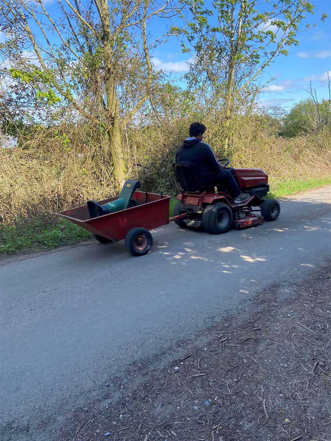 A boy travels along the road on a sit-on lawn mower in Walton Highway