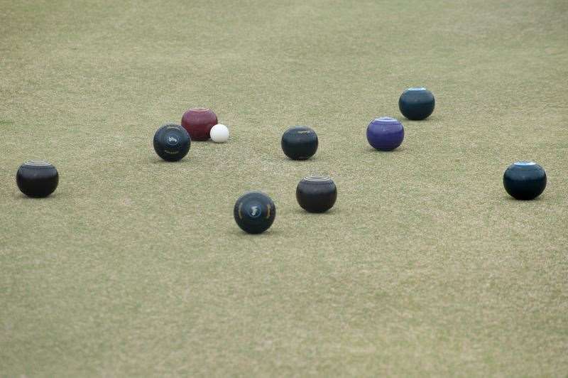 Bowling balls lying around a jack on a bowling green in a game of lawn bowls with copyspace below (9377153)