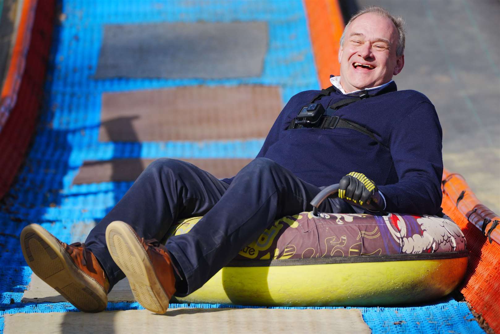 Sir Ed Davey raced down a tube track in a rubber ring during a visit to Gloucester (Ben Birchall/PA)