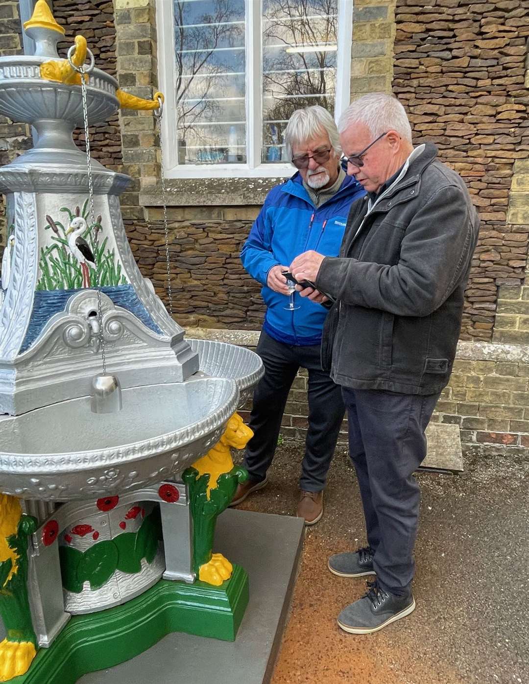 Tom Jones shows pictures of the fountain when it was located in his family's garden to museum volunteer David Bates