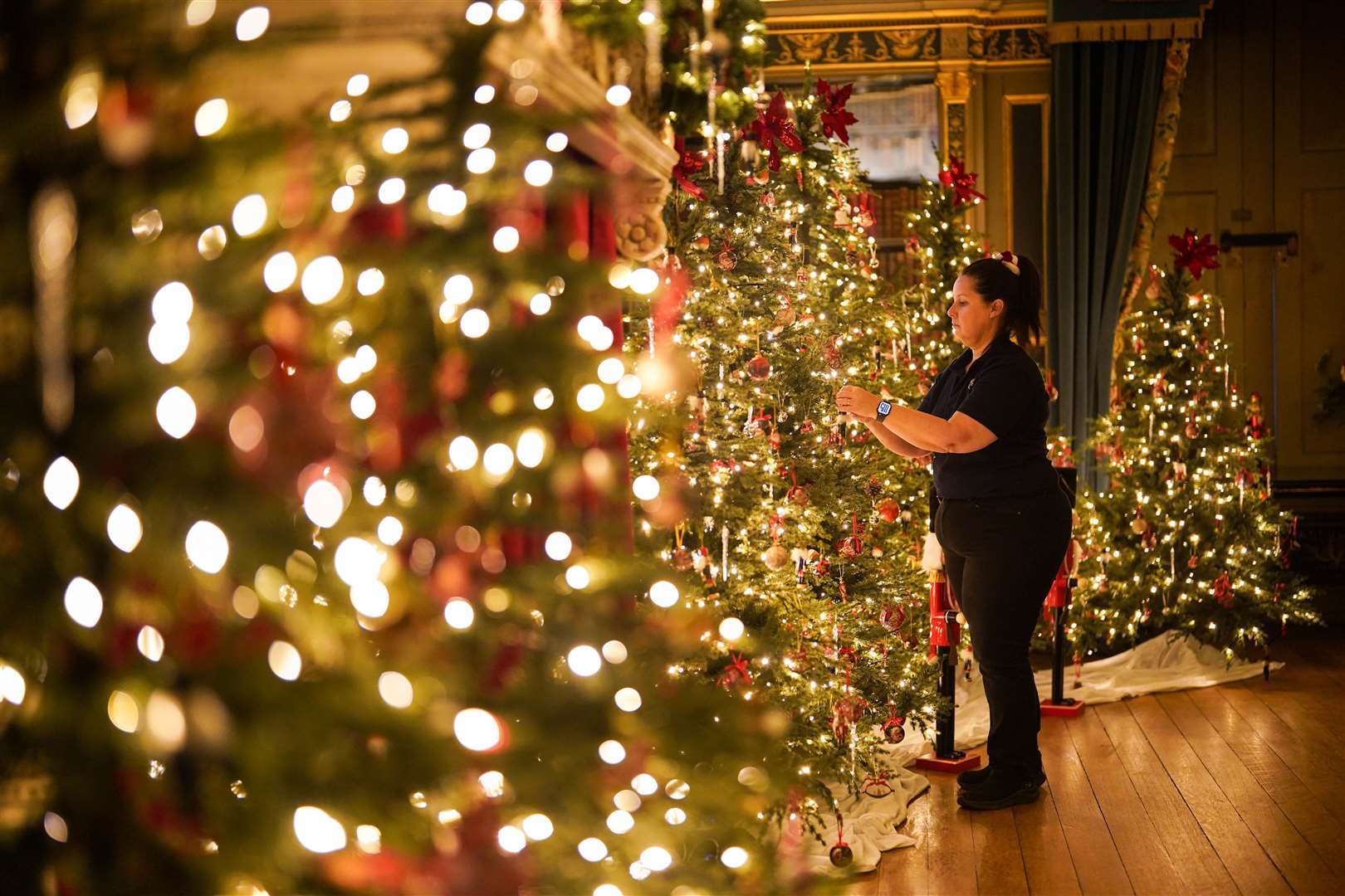 Val Goldman put the finishing touches to the Christmas trees in the Blue Boudoir at Warwick Castle (Jacob King/PA)