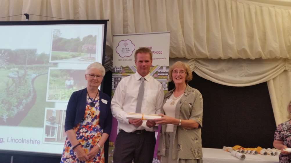 GOLD BLOOM: Spalding in Bloom representatives Christine Lawton (left) and Angela Newton receive the EMIB Gold Award on behalf of the town from Nigel Fox, managing director of Amethyst Horticulture of Kent. Photo supplied.