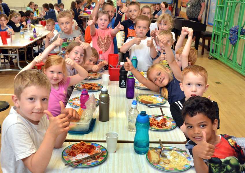 Year 1 pupils give their meals the thumbs-up. Photo by Tim Wilson.