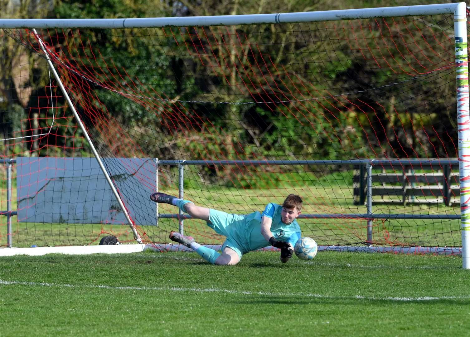 Parson Drove (grey and orange) v Holland (blue). Chris Brazil just fails to stop Holland from taking the lead from the penalty spot