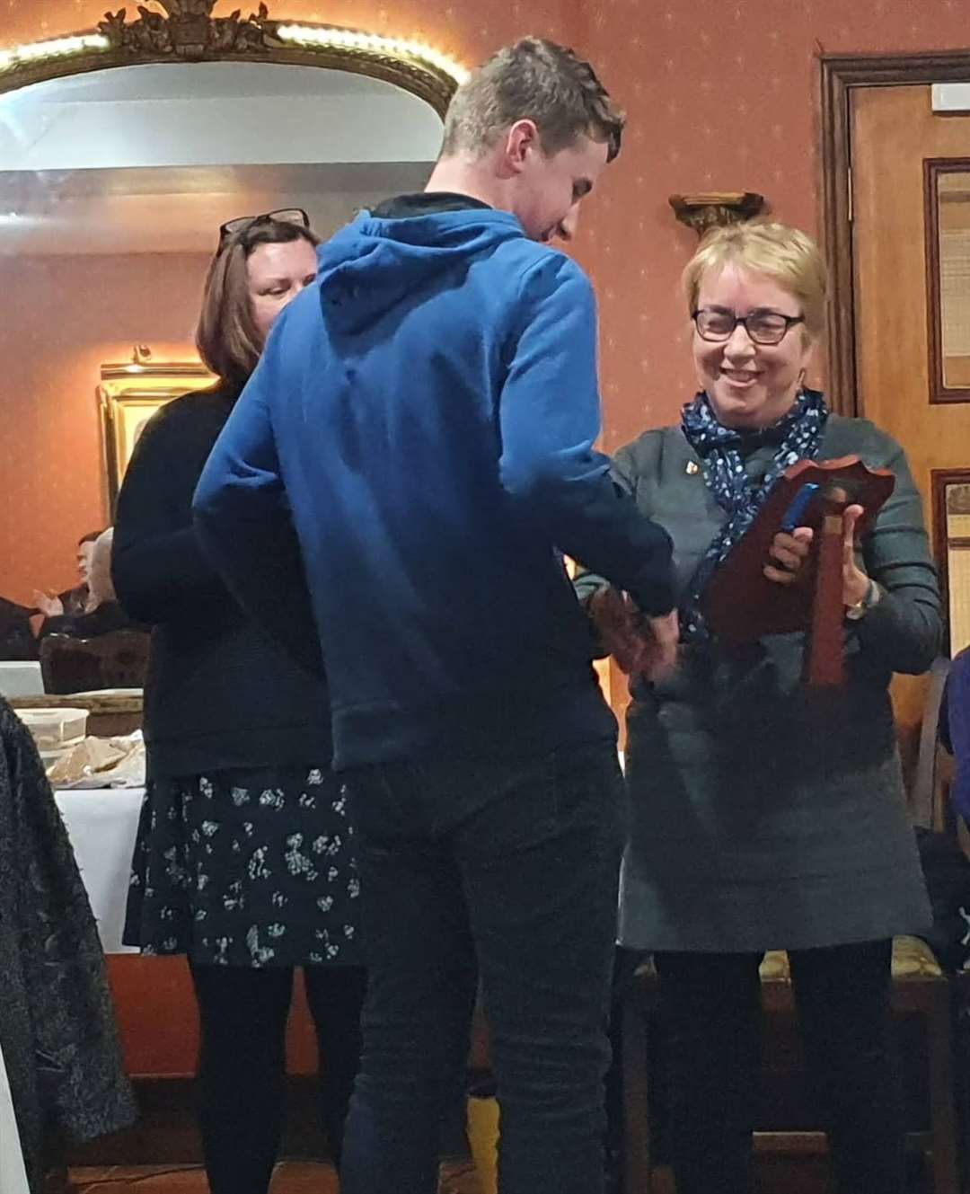 Winner of the youth award, Marcus Neve, receives the shield from Elaine King.