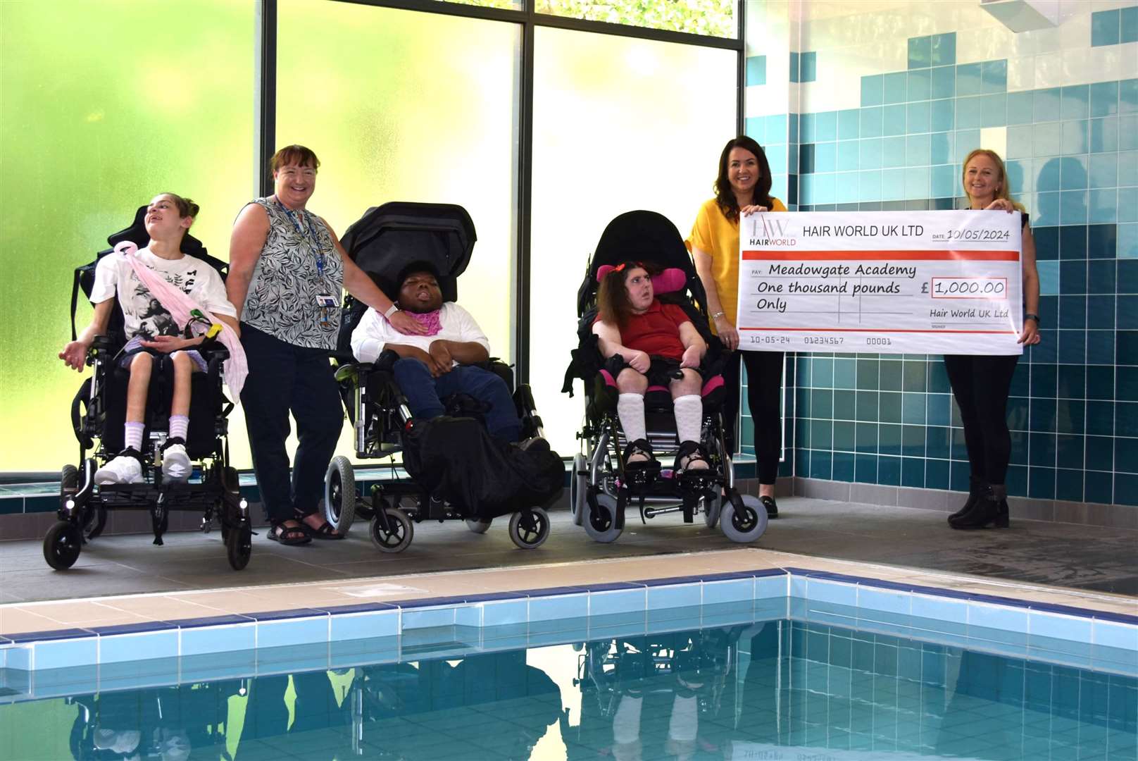 Pupils at Meadowgate with the £1,000 cheque and directors of Hair World in Wisbech