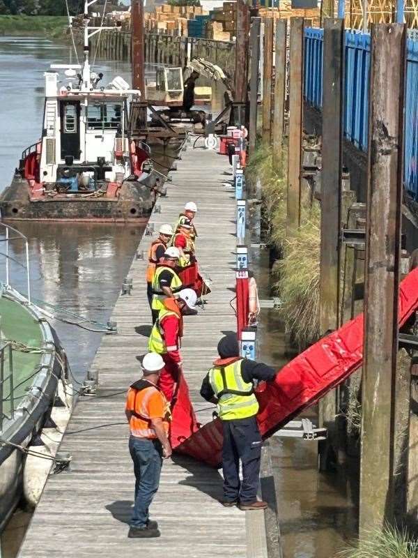 Teams deploy the oil spill containment boom.