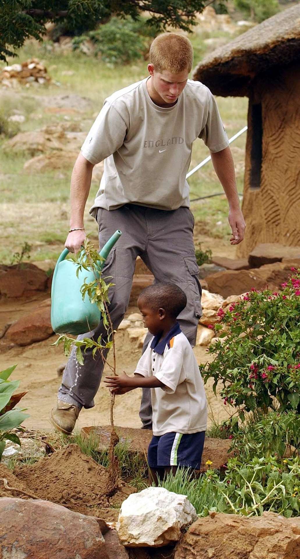 Harry and four-year-old Mutsu Potsane planting a peach tree together at the Mants’ase Children’s Home in Lesotho in 2004 (John Stillwell/PA)