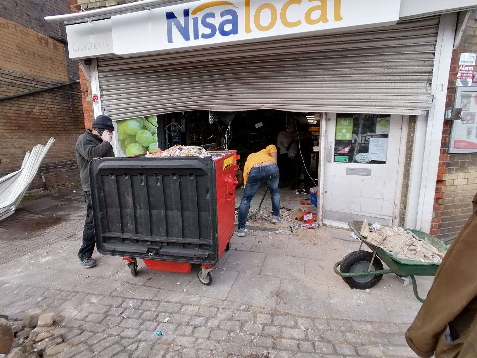 Staff clear rubble from the damaged shop front. (54143542)