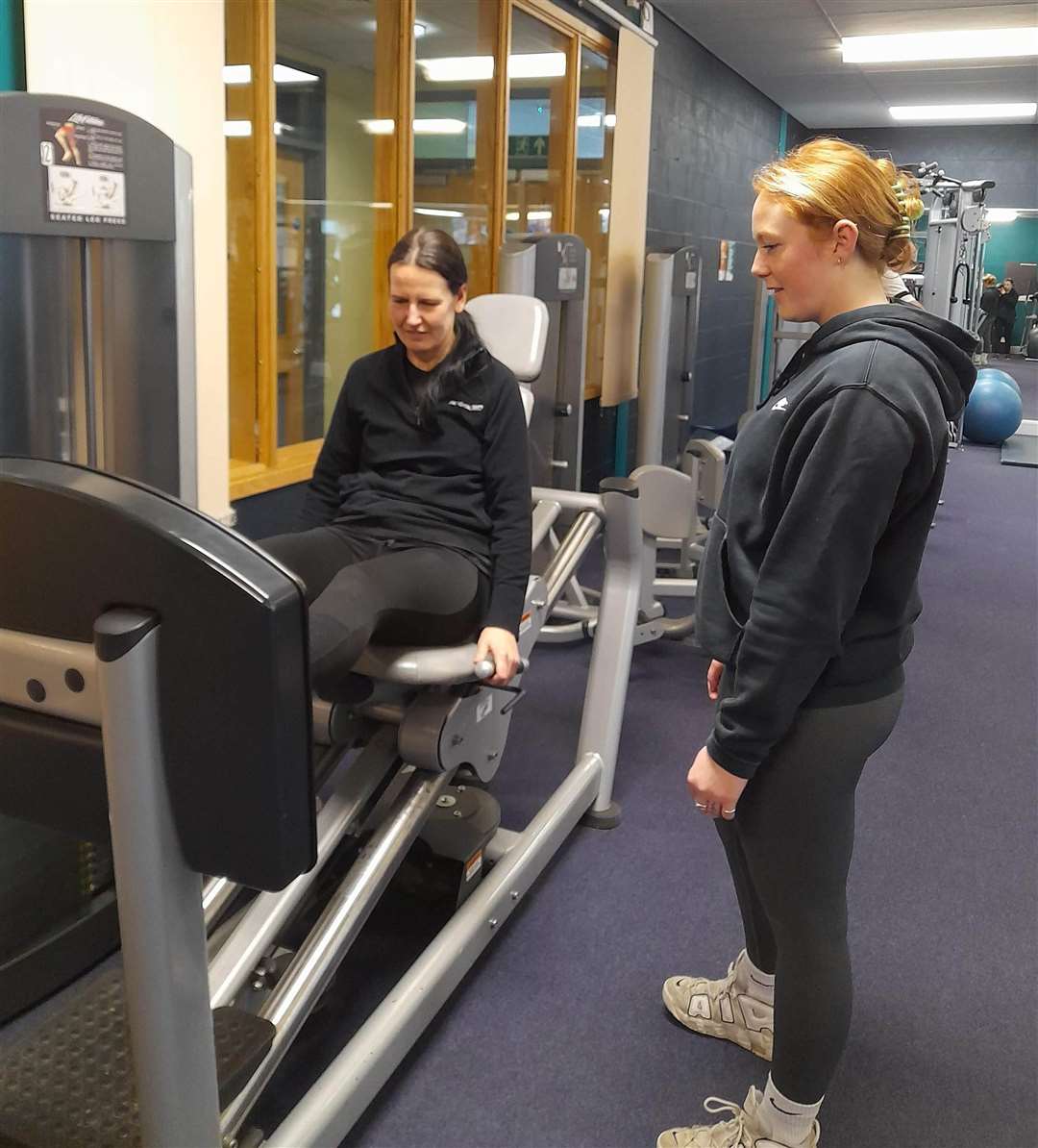 Personal trainer Violet Thrall shows reporter Kate Chapman how to use the gym equipment