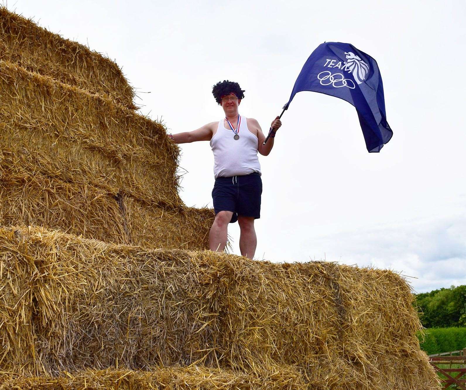 Skylark staff on straw bales holding TeamGB flag.