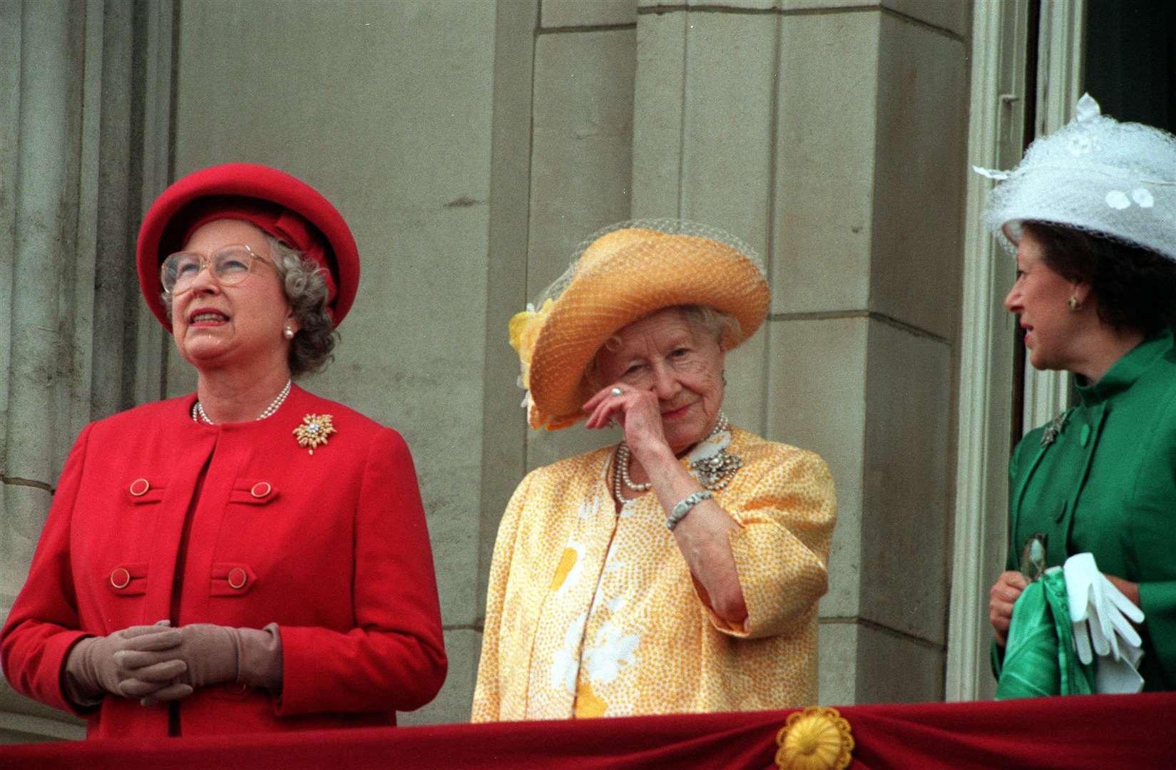 The Queen Mother wipes her eye as she stands on the Buckingham Palace balcony during the 50th anniversary of VE Day with the late Queen Elizabeth II and Princess Margaret (PA)