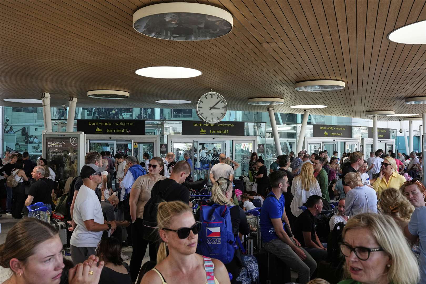 Passengers wait outside Lisbon Airport during a nationwide power outage (Armando Franca/AP)