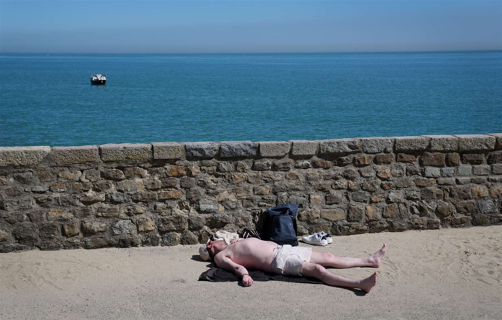 A man relaxes in the sunshine next to the harbour wall in Folkestone, Kent (Gareth Fuller/PA)