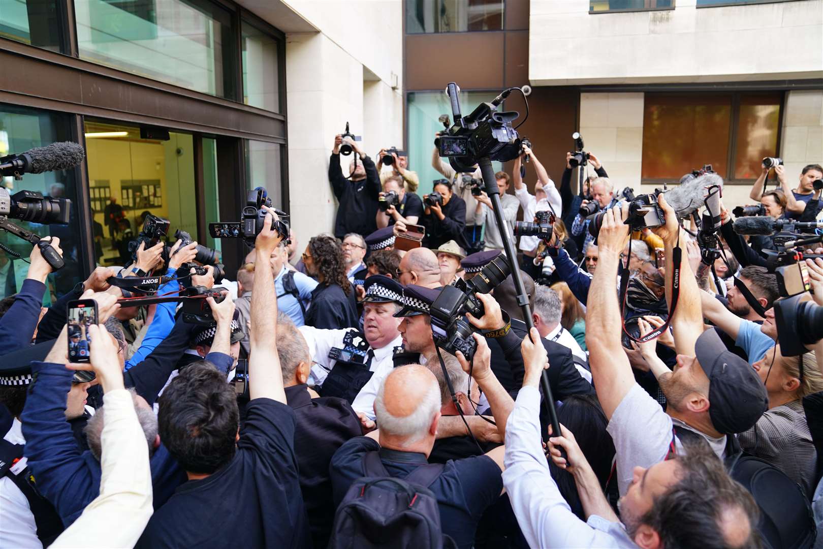 Photographers surround Russell Brand as he arrives at court (James Manning/PA)