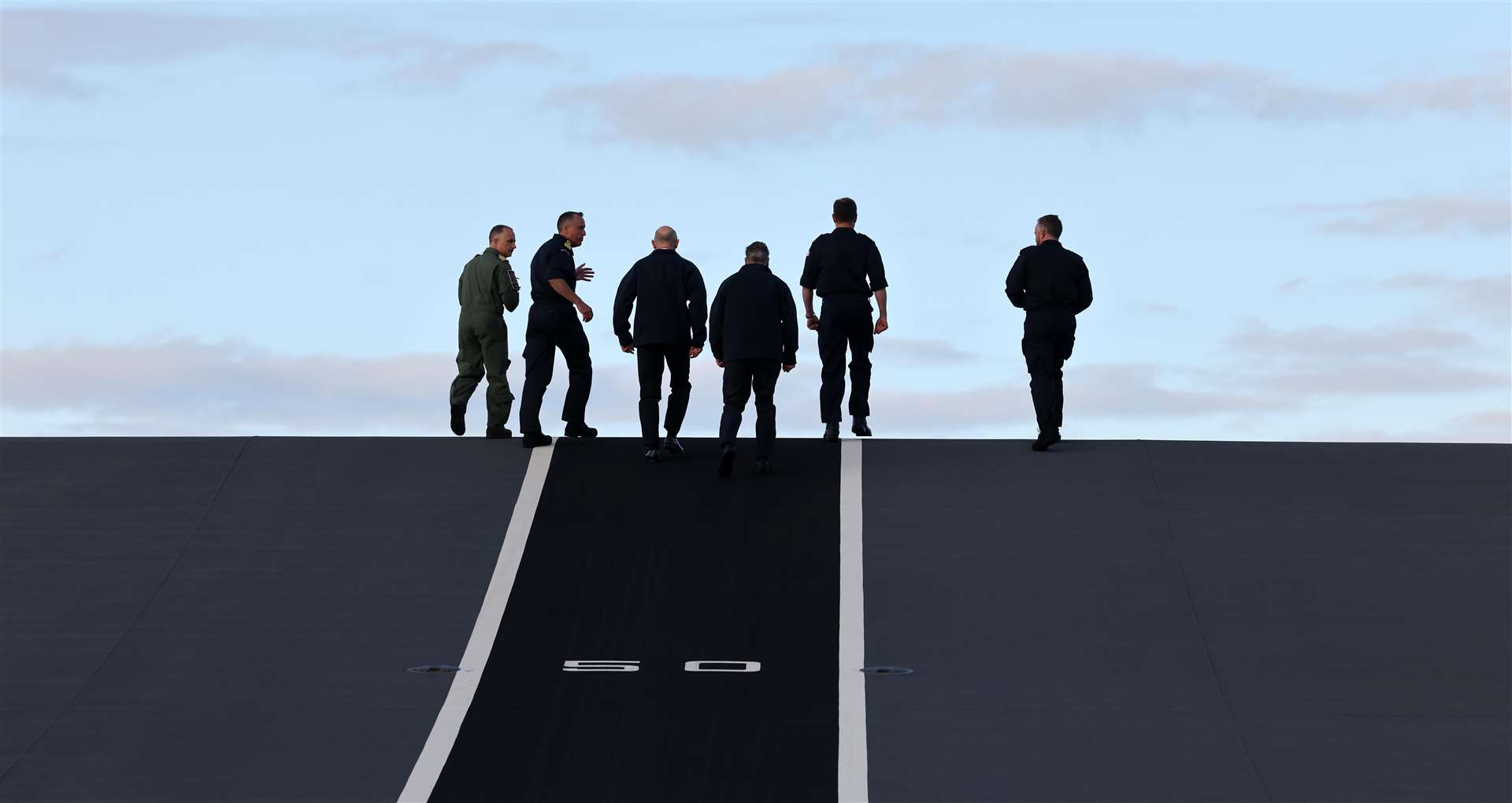 Sir Keir Starmer walks up the F-35 jet take off ramp on the deck of the HMS Prince of Wales (Richard Pohle/PA)