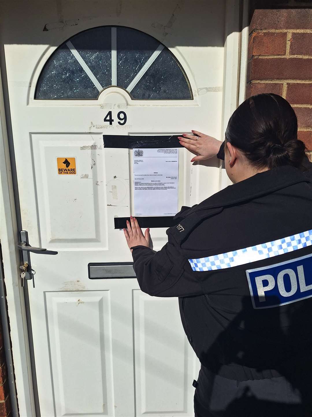 A police officer attaches the closure order the to property's front door