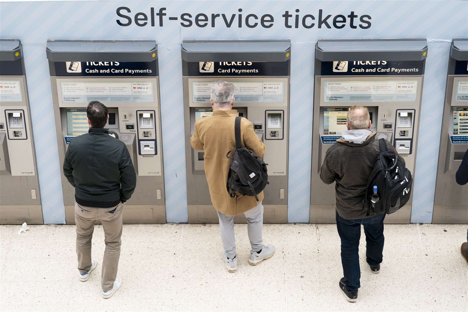 People use a ticket machine at Waterloo train station in London (Kirsty O’Connor/PA)