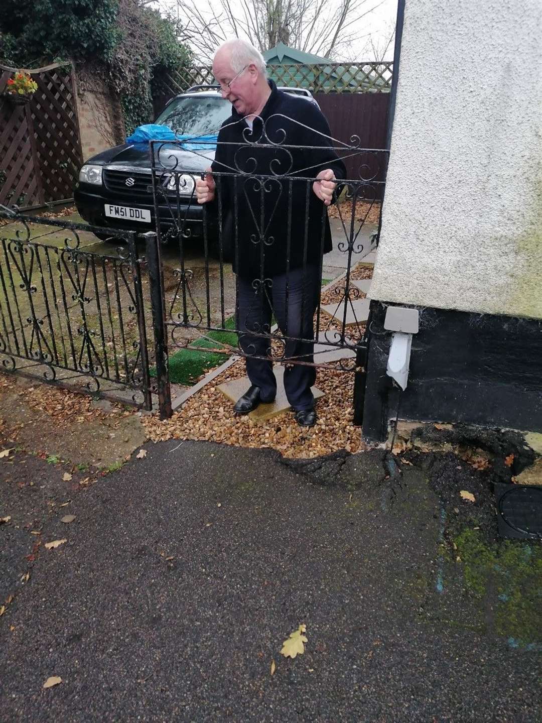 Chris Stone holds his gate up to demonstrate how far his driveway has sunk. (43350647)