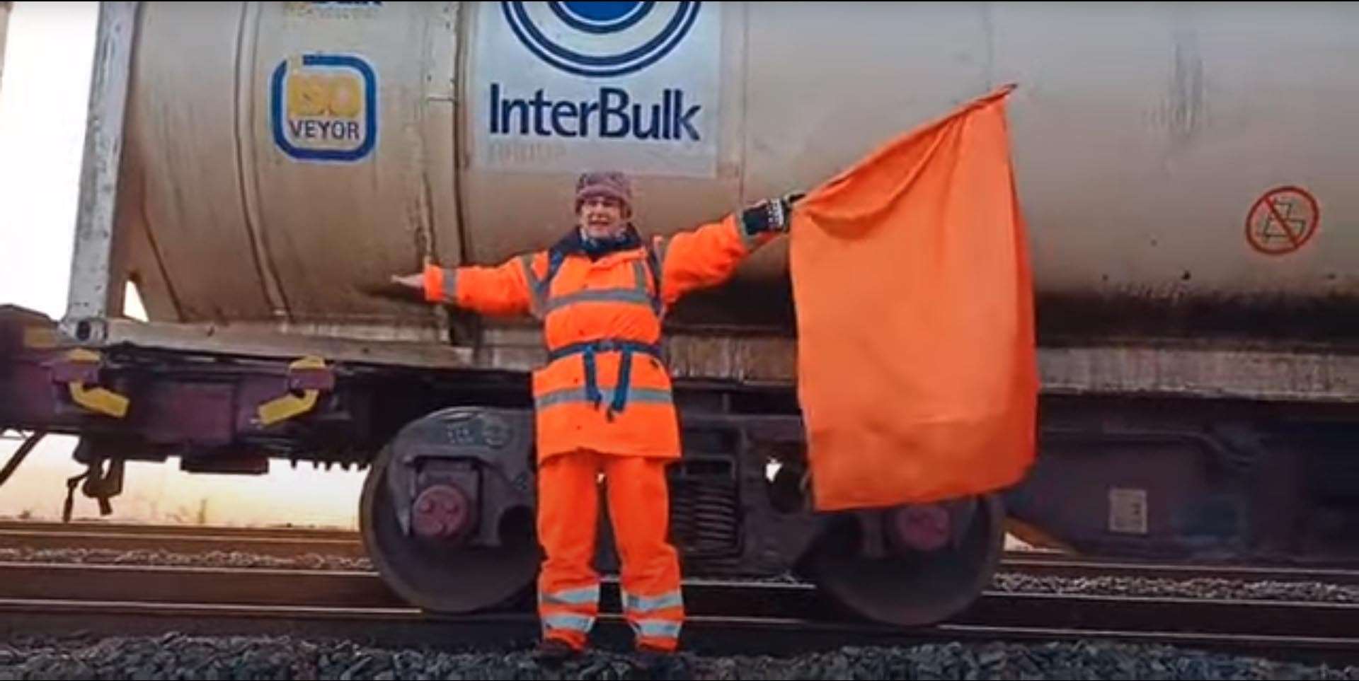 Retired GP Diana Warner waving an orange flag having stopped a 400-metre empty freight train near Drax power station (Axe Drax/PA)