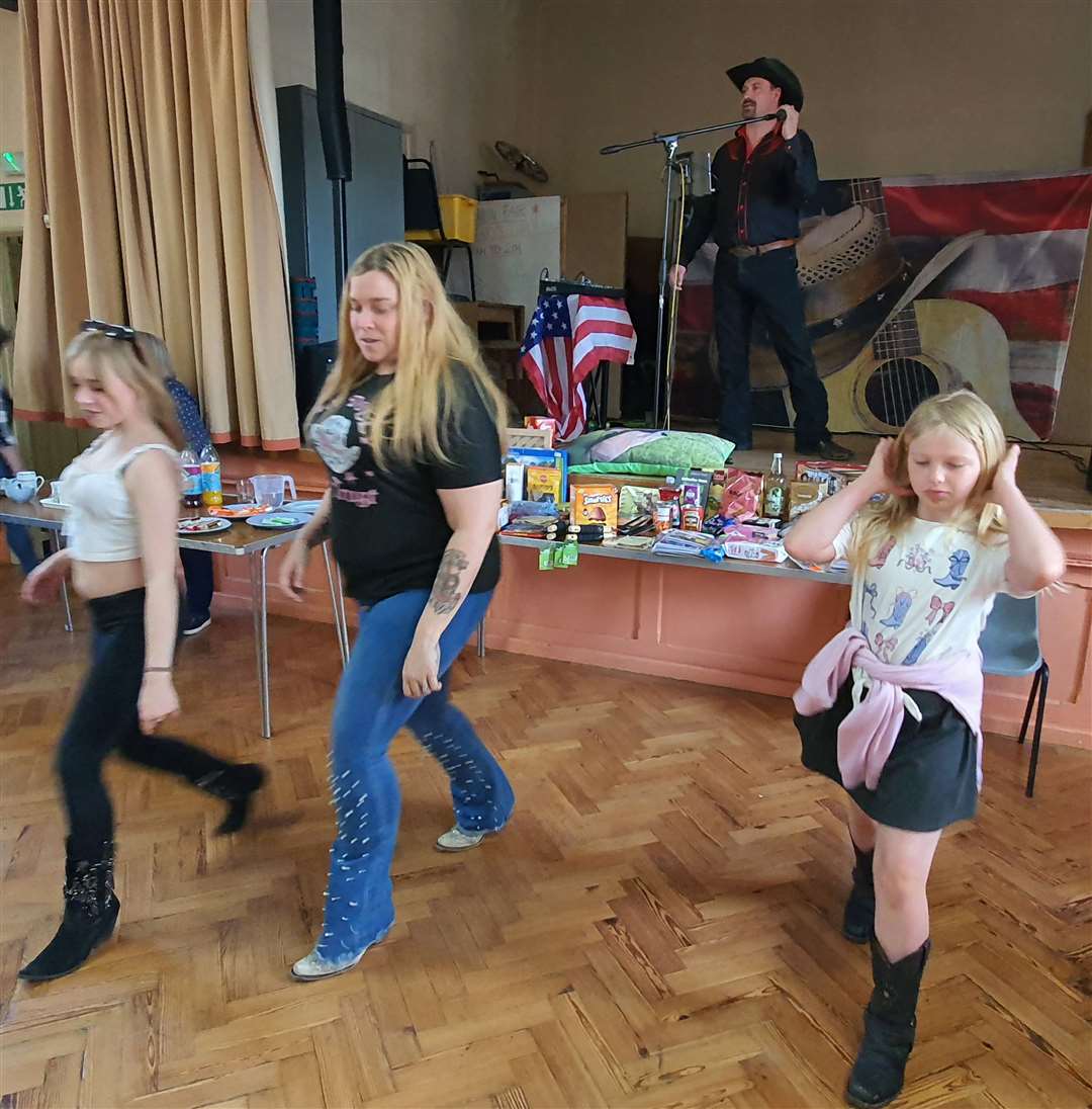 Michaela Bennettoo line dances with her daughters Abi, 12, and Kaitlyn, 11 - as husband Andy Phoenyx sings on stage