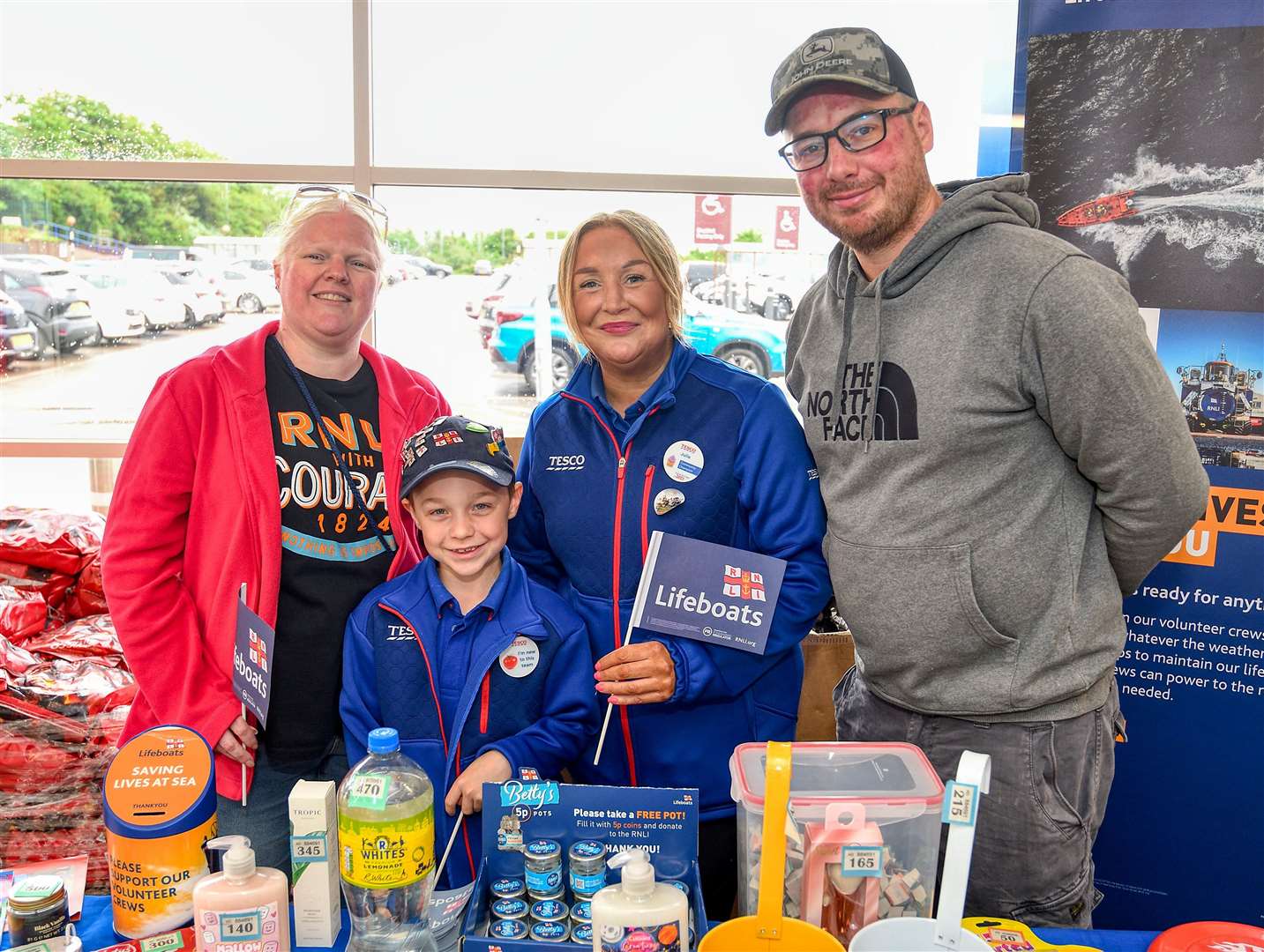 Johnathon Jarvis with Julie Bushby from Tesco and mum and dad Lee and Kayleigh at the tombola store they ran. Picture: RNLI/Chris Bishop