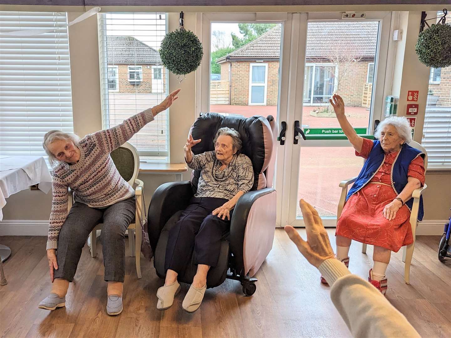 Norah (left) enjoying armchair yoga with other residents (62502028)