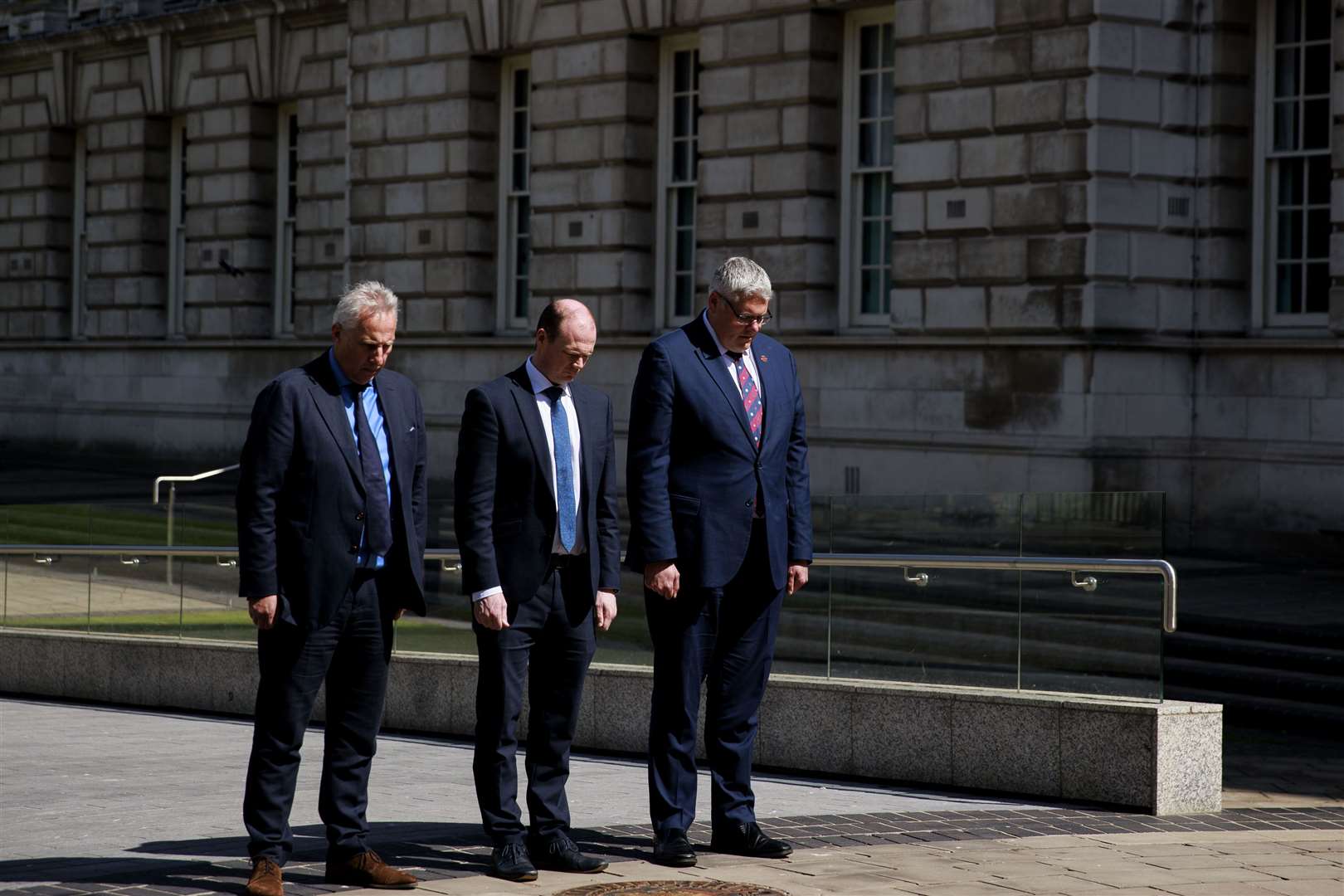 Ian Paisley Jr., Communities Minister Gordon Lyons and DUP leader Gavin Robinson MP observe the two-minute silence at Belfast City Hall Cenotaph (Liam McBurney/PA)