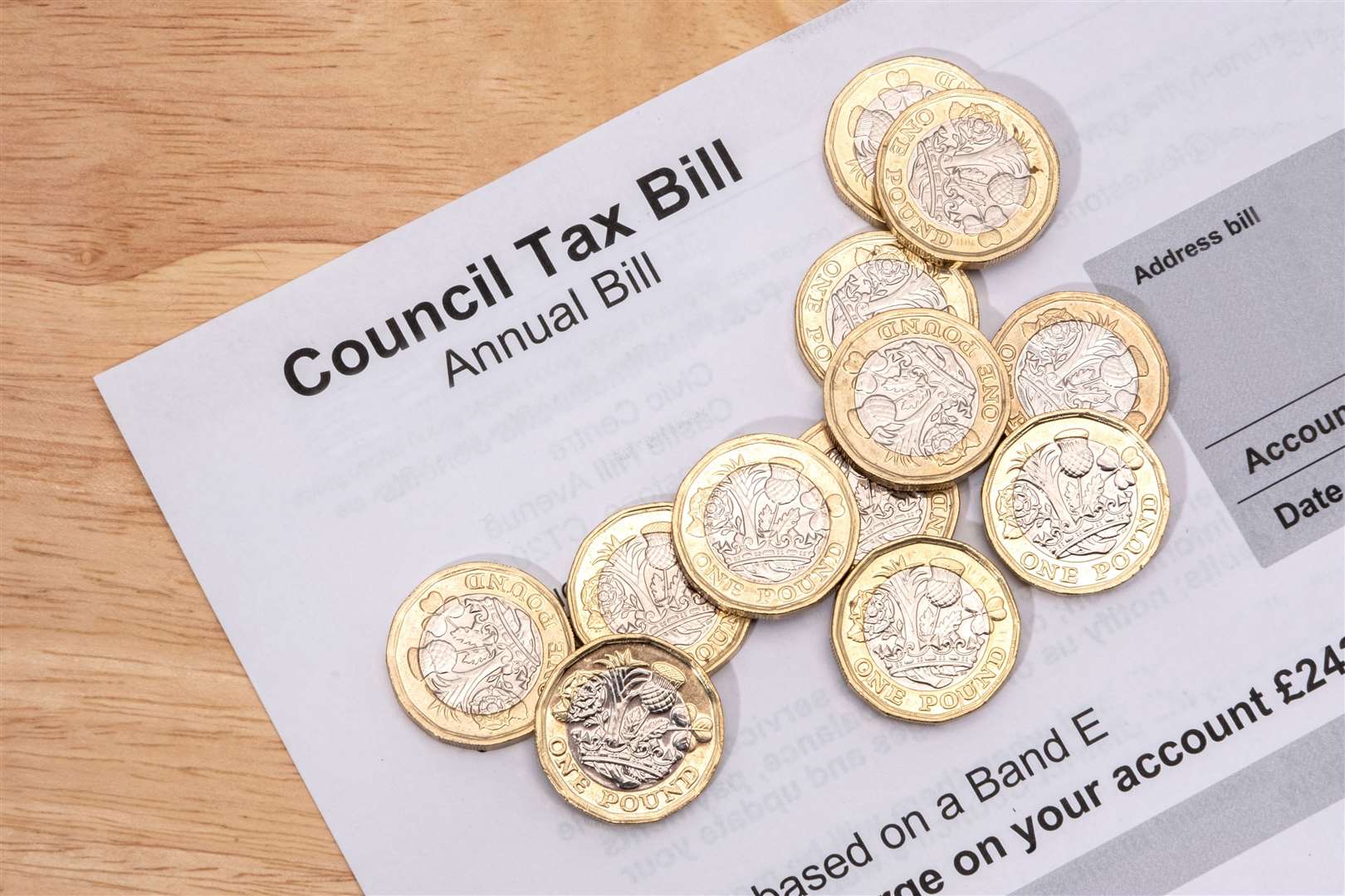 UK one pound coins placed on a Council Tax Bill.