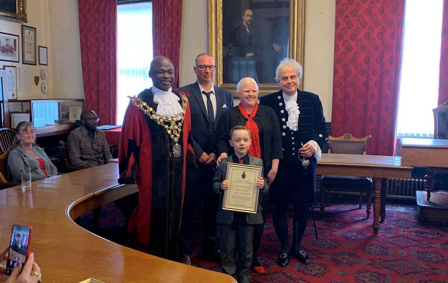 Young fundraiser Johnathan Jarvis with his certificate pictured with his proud family and mayor Sidney Imafidon and the High Sheriff, David Way.