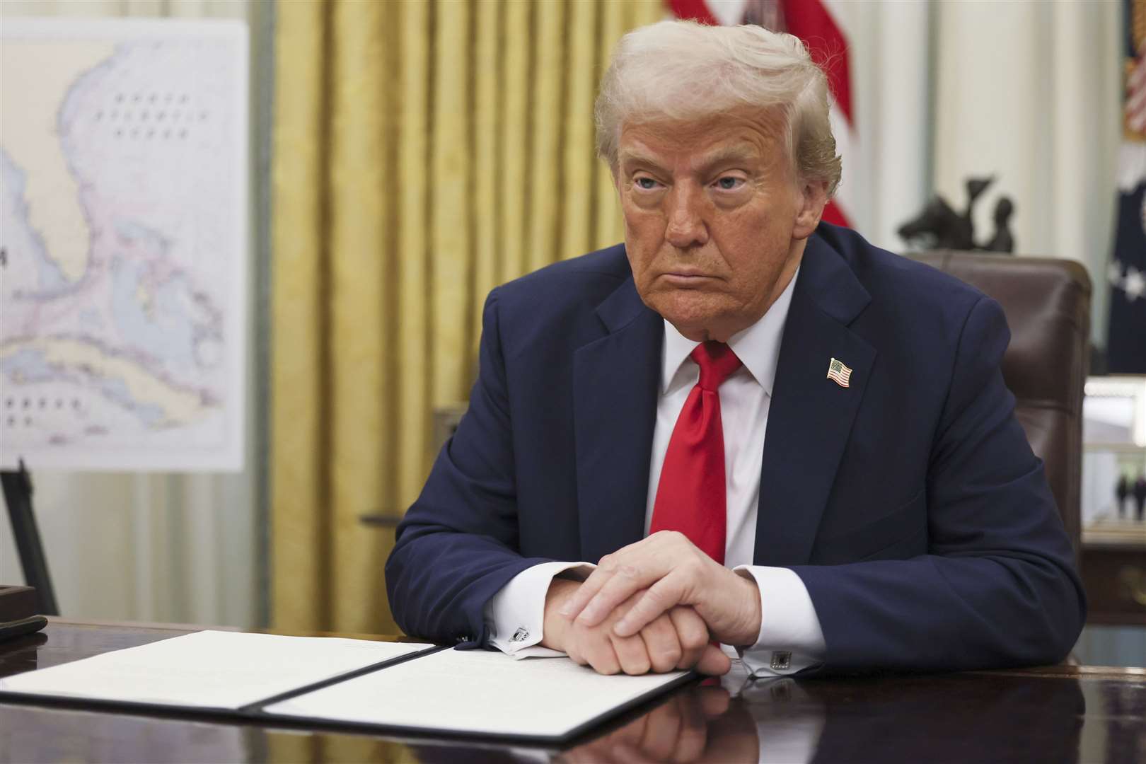 President Donald Trump listens to a question from a reporter before signing an executive order in the Oval Office of the White House (AP photo)