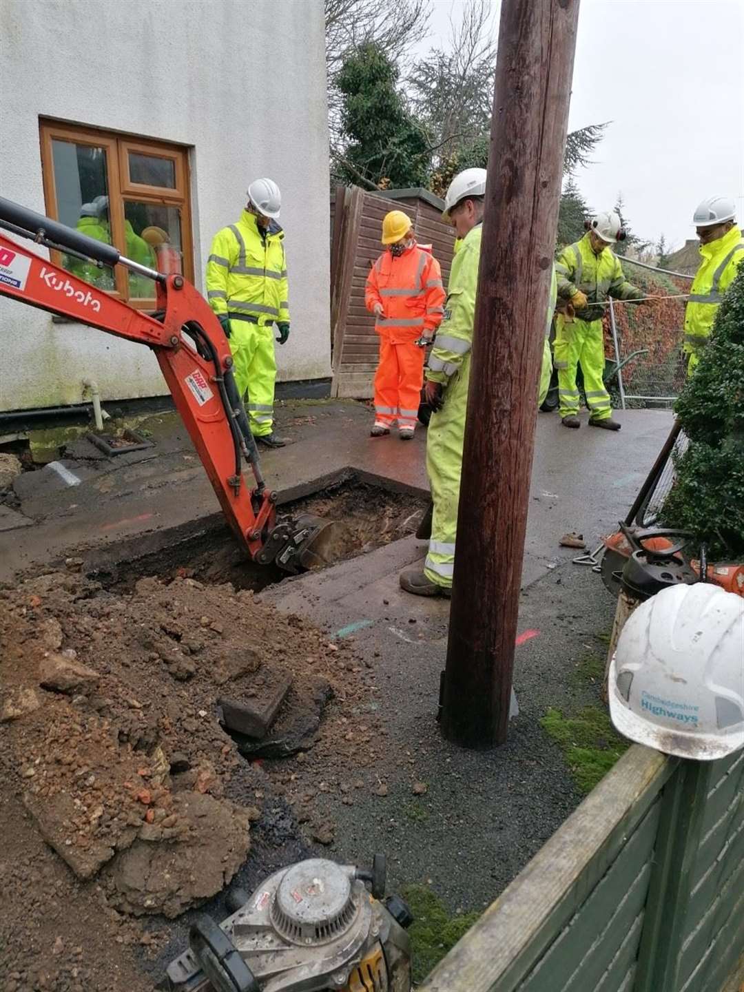 Workmen dig trench one watched by Councillor Jan French, in orange, who has been trying to help the residents get answers. (43350659)