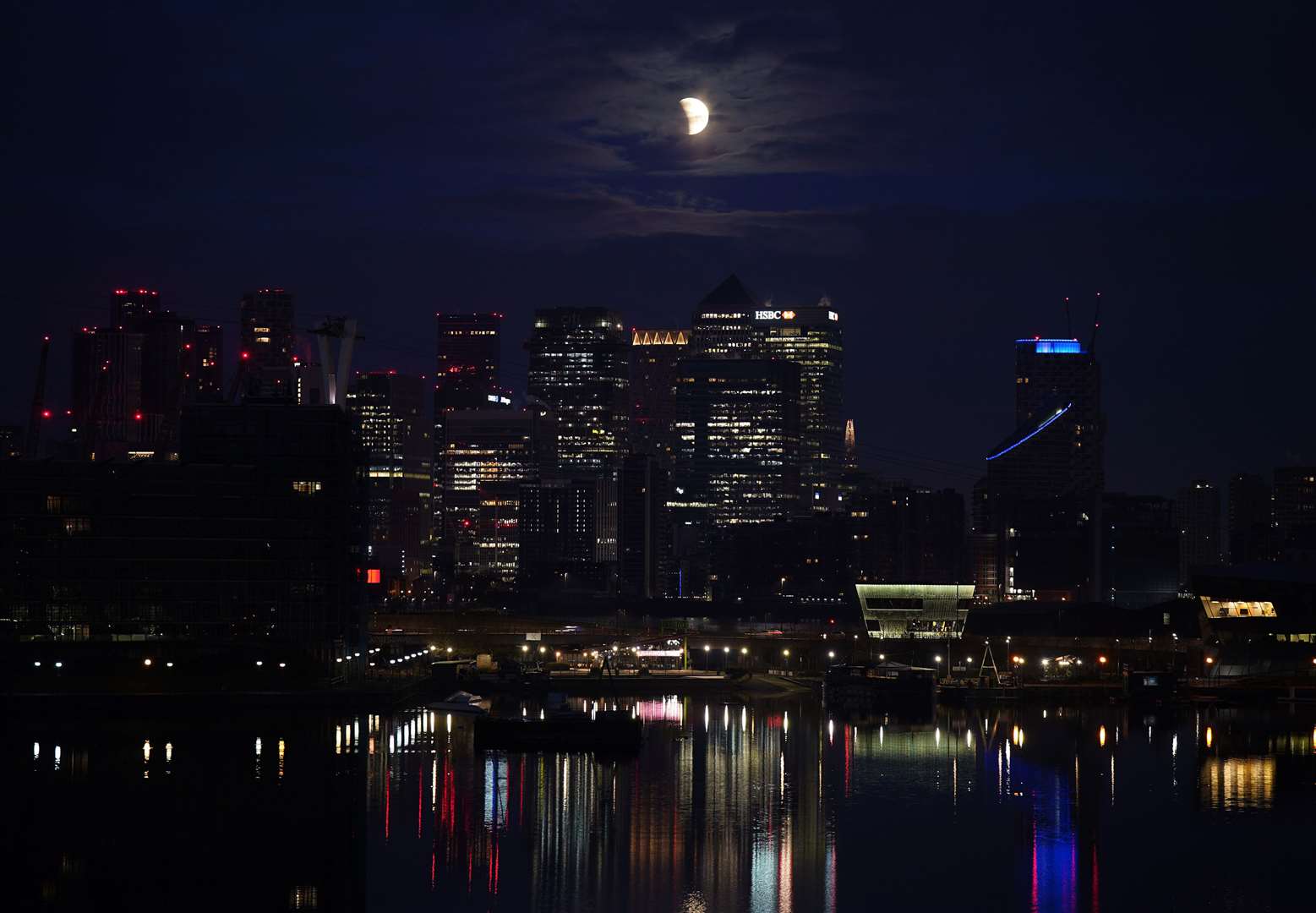 A lunar eclipse is visible above Canary Wharf in London as the full moon passes into Earth’s shadow (Yui Mok/PA)