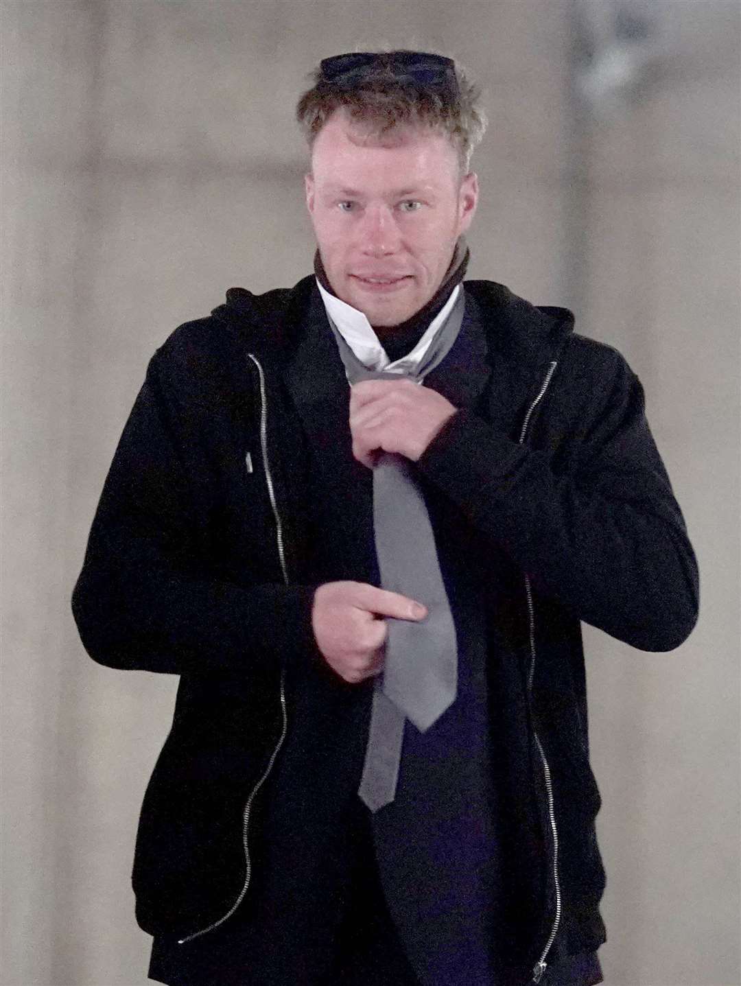 Adam Carruthers, 31, adjusts his clothing as he arrives to attend Newcastle Crown Court where he is accused of criminal damage after the felling of the Sycamore Gap tree (PA)